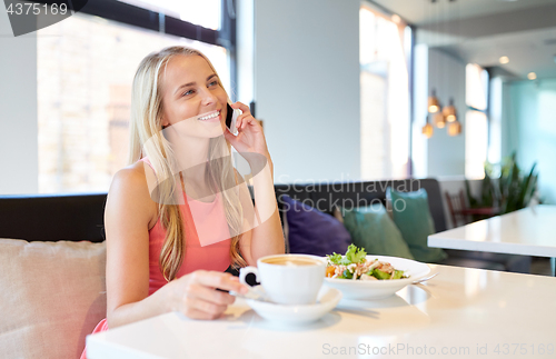 Image of woman with coffee calling smartphone at restaurant
