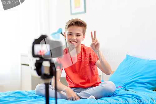 Image of happy boy with camera recording video at home