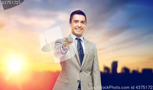 Image of smiling businessman pointing at you over city