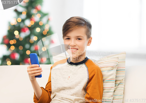 Image of boy playing on smartphone at home at christmas