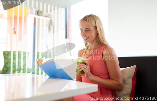 Image of woman with drink reading book at cafe