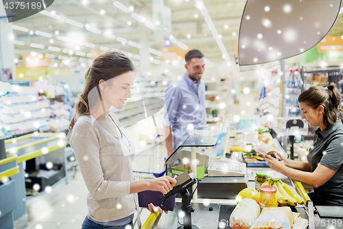 Image of couple buying food at grocery store cash register