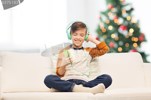 Image of boy with smartphone and headphones at christmas