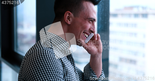 Image of Business Man Talking On Cell Phone, Looking Out Office Window