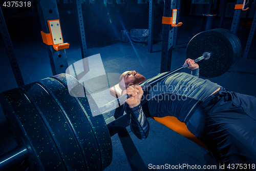 Image of Portrait of super fit muscular young man working out in gym with barbell