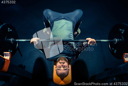 Image of Portrait of super fit muscular young man working out in gym with barbell