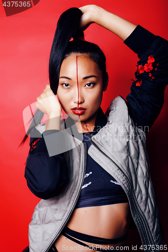 Image of young pretty asian girl posing cheerful on red background, fashion style makeup and hair, lifestyle modern orient people concept