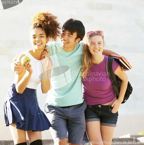 Image of cute group of teenages at the building of university with books huggings, back to school