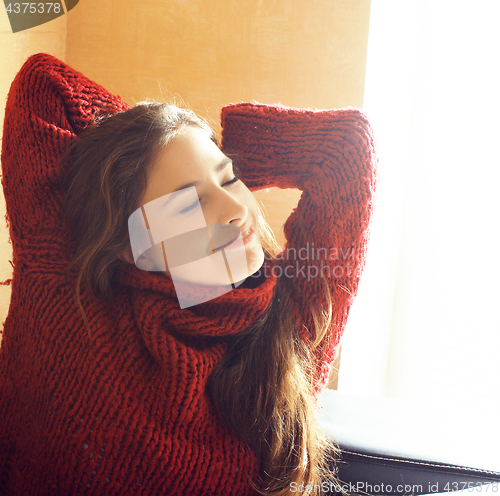 Image of young pretty real woman in red sweater and scarf all over her fa