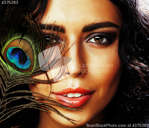 Image of young sensitive brunette woman with peacock feather eyes close up on green smiling, lifestyle people concept macro