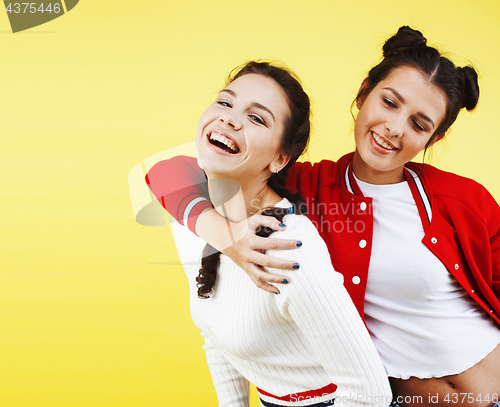 Image of lifestyle people concept: two pretty young school teenage girls having fun happy smiling on yellow background