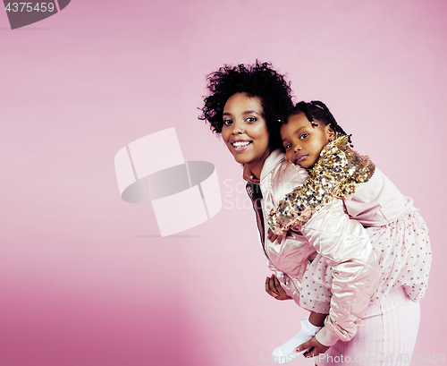 Image of young pretty african-american mother with little cute daughter hugging, happy smiling on pink background, lifestyle modern people concept
