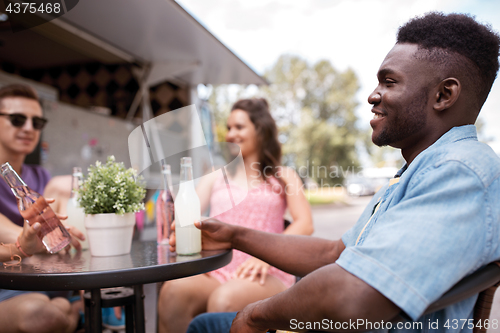 Image of friends with drinks sitting at table at food truck