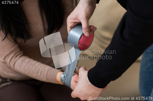 Image of criminal tying woman with adhesive tape