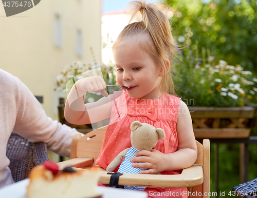 Image of little girl with spoon eating outdoors