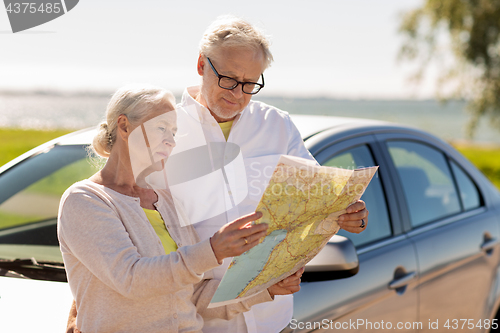 Image of senior couple with car looking for location on map