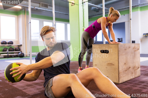 Image of woman and man with medicine ball exercising in gym