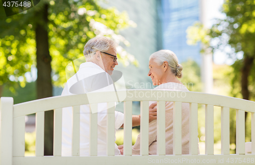 Image of happy senior couple sitting on bench at park