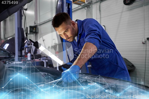 Image of mechanic man with lamp repairing car at workshop