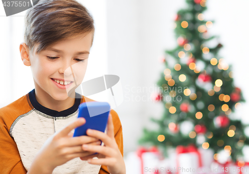 Image of close up of happy boy with smartphone at christmas