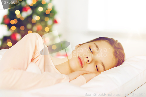 Image of girl sleeping in bed over christmas tree 