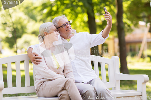 Image of senior couple taking selfie by smartphone at park