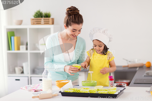 Image of happy mother and daughter baking cupcakes at home