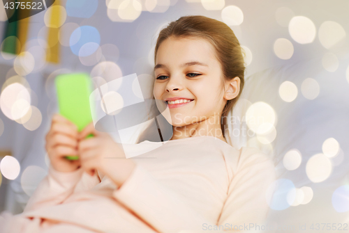 Image of happy girl in bed with smartphone over lights