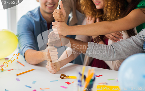 Image of team making thumbs up hand sign at office party