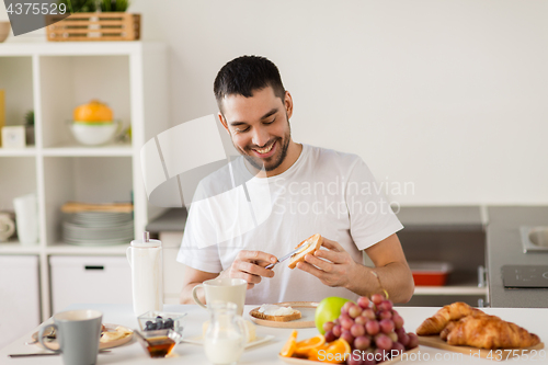 Image of man eating toast with coffee at home kitchen