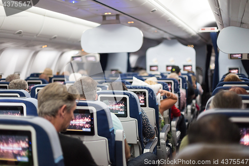 Image of Interior of large commercial airplane with passengers on seats waiting to taik off.