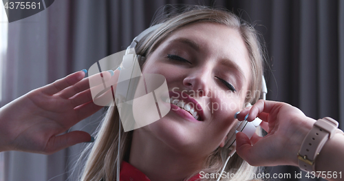 Image of Lovely Blond Woman Listening To Music while resting on couch