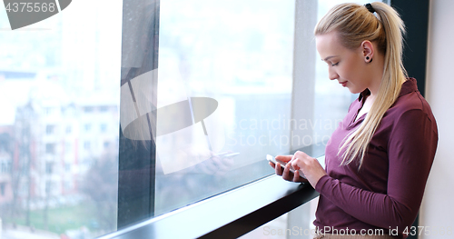 Image of Elegant Woman Using Mobile Phone by window in office building