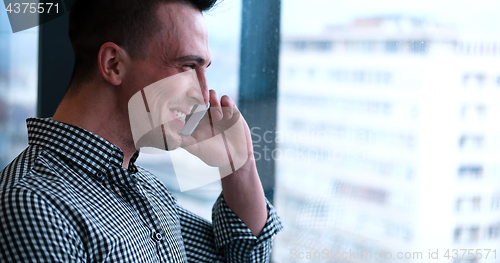 Image of Business Man Talking On Cell Phone, Looking Out Office Window