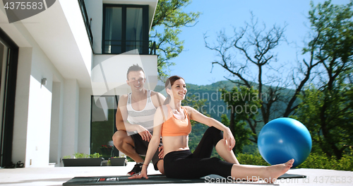 Image of Couple Doing Stretching Exercises Together in front of luxury vi