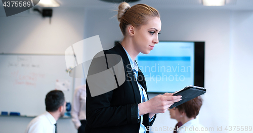 Image of Businesswoman using tablet with coworkers in backgorund having m