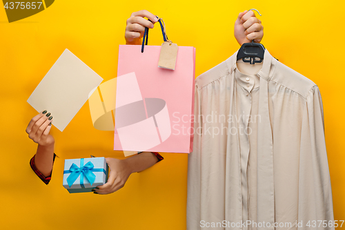 Image of Female hand holding bright shopping bag and gifts