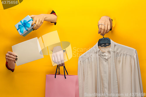 Image of Female hand holding bright shopping bag and gifts