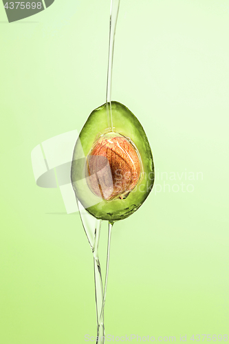 Image of Fresh avocado and oil on green background