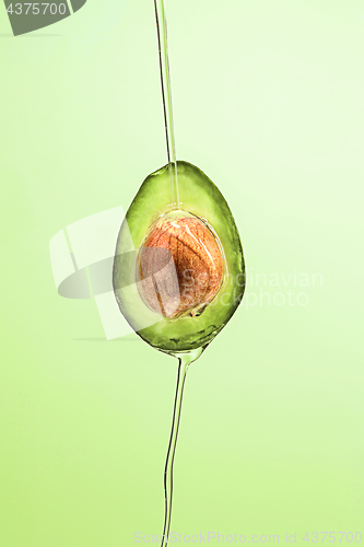 Image of Fresh avocado and oil on green background