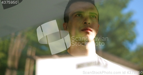 Image of reflection of sad man looking through window