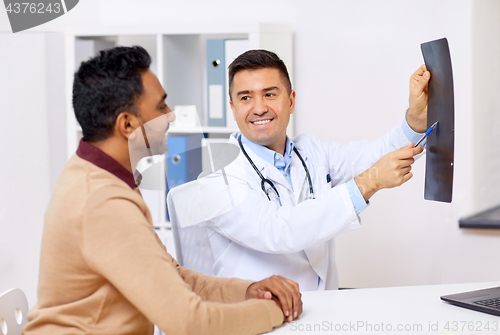 Image of doctor with x-ray and male patient at clinic