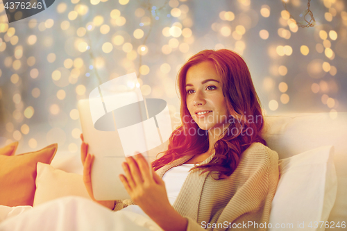 Image of happy young woman with tablet pc in bed at home