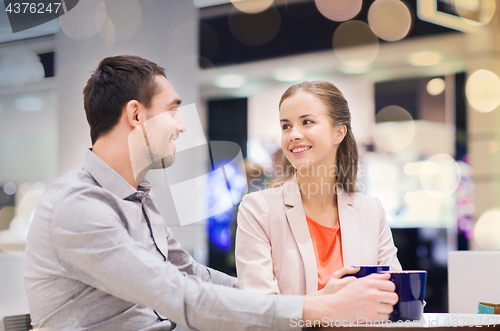 Image of happy couple with shopping bags drinking coffee