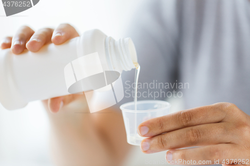 Image of woman pouring syrup from bottle to medicine cup