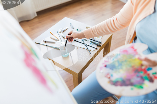 Image of artist washing paintbrush at art studio