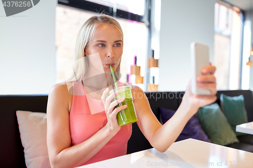 Image of woman with smartphone taking selfie at restaurant