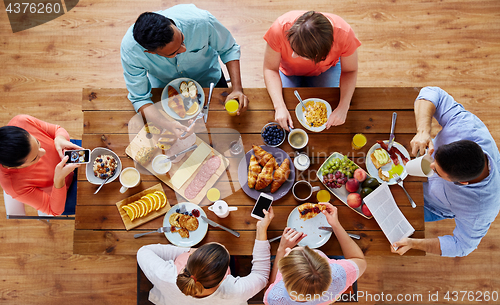 Image of people with smartphones eating food at table