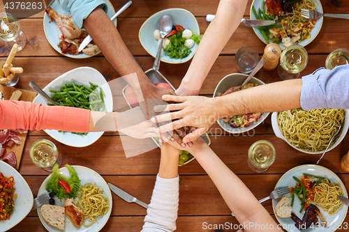 Image of people holding hands together over table with food