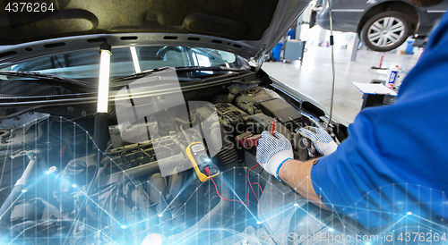 Image of auto mechanic man with multimeter testing battery